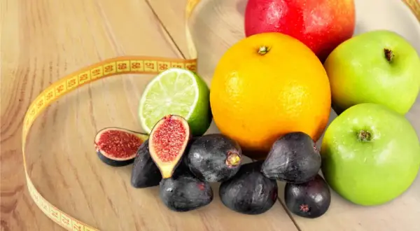 Jabłka, pomarańcza, figi, limonka i miarka krawiecka – idealne owoce na diecie.