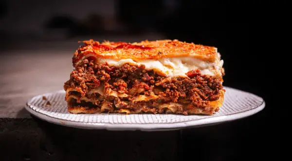 Ein Stück Lasagne mit Hackfleisch und Käse auf einem Teller. Perfekt, wenn man sich fragt, wie lange Lasagne im Ofen braucht.