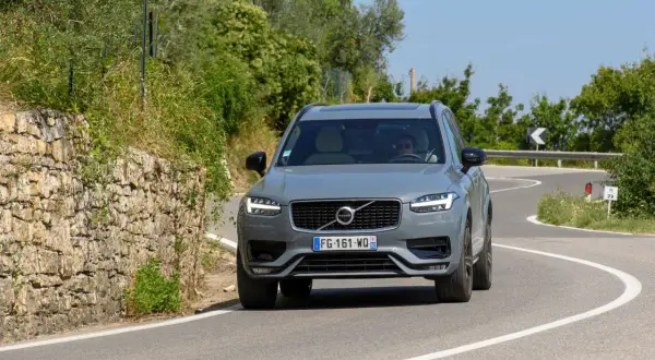 Szary Volvo XC90 2020 na krętej drodze wśród zieleni.