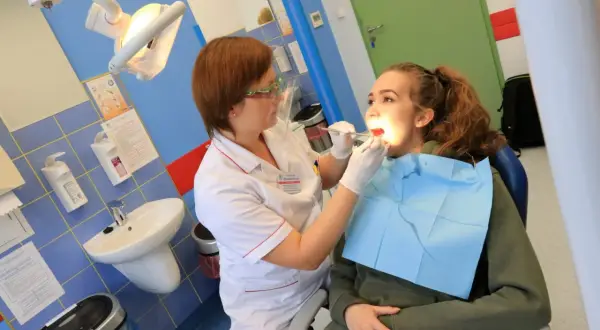 Dentystka bada zęby młodej pacjentki w gabinecie stomatologicznym.