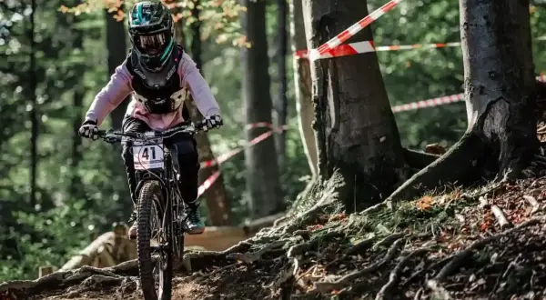 Rowerzystka w kasku z numerem 41 zjeżdża po leśnej ścieżce. To świetne **trasy rowerowe Śląsk** dla miłośników adrenaliny.