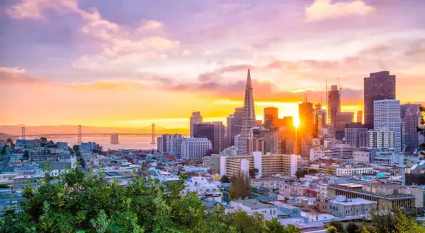 Zachód słońca nad San Francisco, idealne miejsce na wakacje w Stanach Zjednoczonych. Most Golden Gate i drapacze chmur w złotej poświacie.
