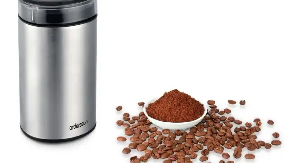 En kaffekvarn i metall bredvid en skål med kaffepulver och bönor. Perfekt för att lära sig hur brygger man kaffe.
