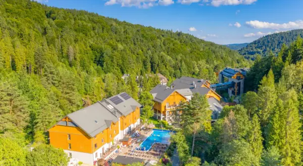 Idealne atrakcje na majówkę: kompleks hotelowy w otoczeniu zielonych lasów, z basenem i miejscami do wypoczynku.