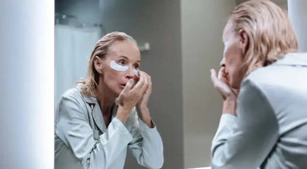 Femme appliquant des patchs sous les yeux, découvrant les matrixyl bienfaits pour une peau rajeunie.