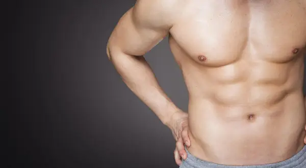 Ein Mann mit definierten Bauchmuskeln und Brust, ein Beispiel für natürlichen Muskelaufbau durch Training und Ernährung.