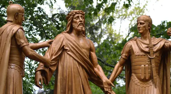 Rzeźba przedstawia Jezusa z koroną cierniową, którego dwaj żołnierze prowadzą, symbolizując różnicę między wolną wolą a przeznaczeniem w teologii chrześcijańskiej.