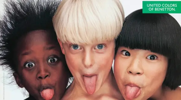 Tre bambini di etnie diverse, in una delle fotografie famose a colori di Oliviero Toscani, fanno la linguaccia.