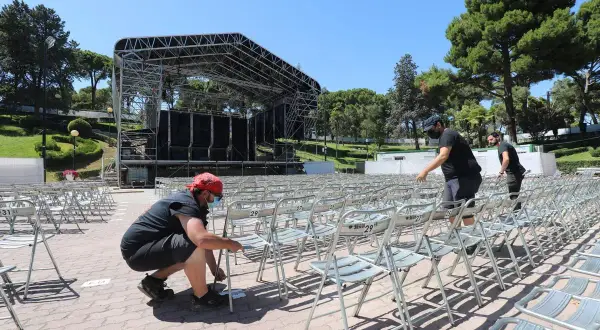 Preparando el escenario para conciertos en el Jardín de Invierno de Zaragoza. Hombres colocan sillas metálicas en filas.