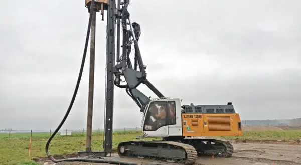 Palownica z operatorem w kabinie, pracująca na budowie.