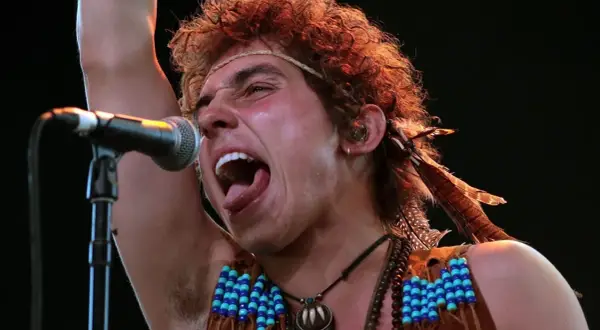 Josh Kiszka z Greta Van Fleet, jeden z członków zespołu, śpiewa z pasją do mikrofonu, ozdobiony piórami i koralikami.