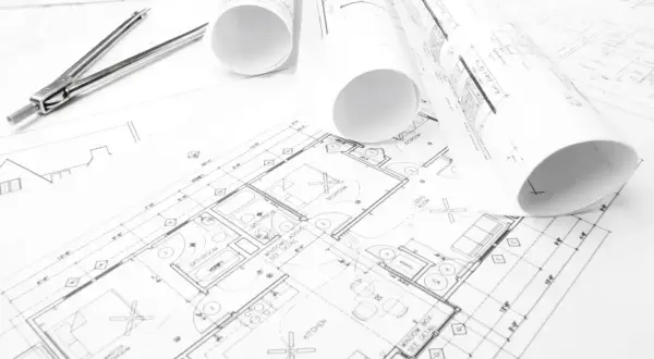 Plany budynków, gdzie szukać inspiracji i rozwiązań architektonicznych. Rysunki techniczne, cyrkiel i rolki z projektami.