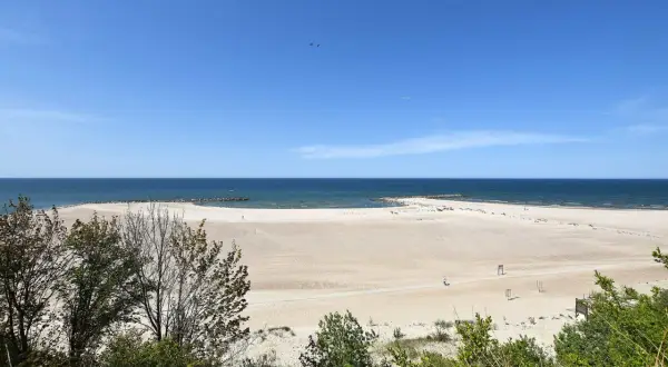 Piękna, szeroka plaża w Jarosławcu, idealna na letni wypoczynek. W oddali widać morze i falochrony.
