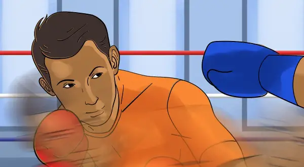 Boxer in orange shirt dodges a blue-gloved punch with a bob and weave motion in a boxing ring.