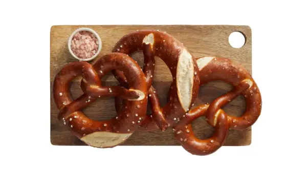 Trzy apetyczne precle z solą na desce, idealne na przekąskę. Zastanawiasz się nad precel Lidl kcal?
