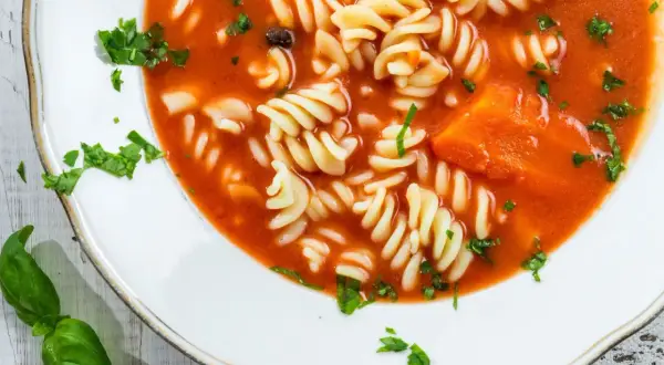 Zupa pomidorowa z makaronem fusilli i kawałkami marchewki. Aby jak zmniejszyć kwasowość zupy, dodaj szczyptę sody.
