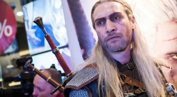 Geralt z Rivii, wiedźmin z blizną na twarzy, z dwoma mieczami za plecami.