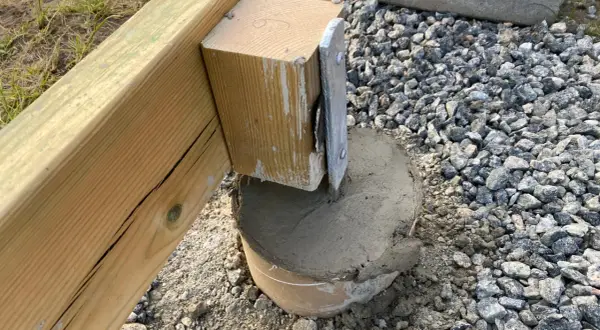 Nygjuten betong runt en stolpe som ska bära en altan. Plintavståndet är viktigt för stabiliteten.