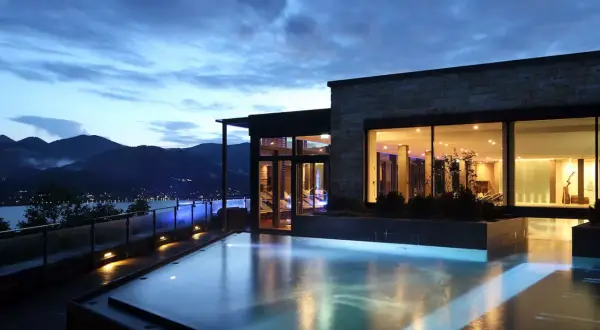 Ein luxuriöser Pool mit Blick auf die Berge und einen See. Perfekt für einen entspannten Urlaub in den Bergen.