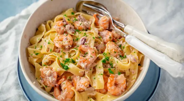 Breite Bandnudeln mit saftigen Garnelen in cremiger Sauce, garniert mit frischer Petersilie. Ein köstliches Gericht mit Nudeln mit Garnelen.