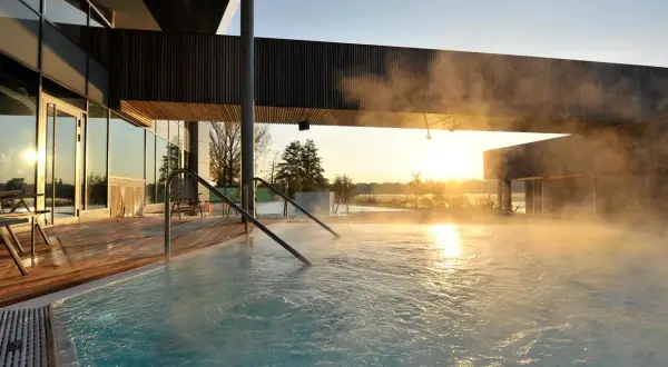 Dampf steigt aus einem Pool auf, während die Sonne über Brandenburg aufgeht. Ein perfekter Ort für einen erholsamen Urlaub.