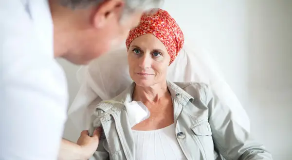 Ärztin spricht mit Patientin, die eine Kopfbedeckung trägt, während sie eine hyperthermie therapie erhält.