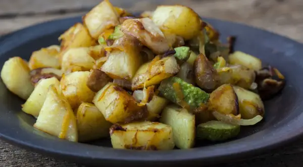 Un piatto invitante di patate e zucchine al forno, dorate e saporite, pronte per essere gustate.