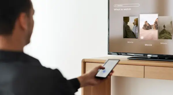 Mężczyzna steruje telefonem, by dowiedzieć się, jak udostępnić internet z telefonu na telewizor i oglądać filmy.