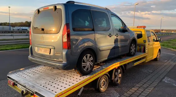 Niebieski Citroen Berlingo na żółtej lawecie. Pomoc drogowa HDI assistance w akcji, holowanie pojazdu po awarii.