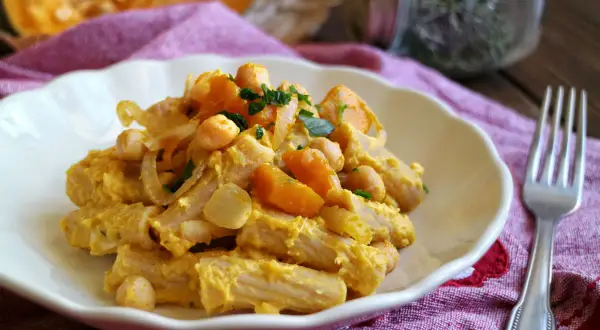 Piatto di pasta con la zucca, ceci e cipolla, guarnito con prezzemolo fresco. Un comfort food autunnale.