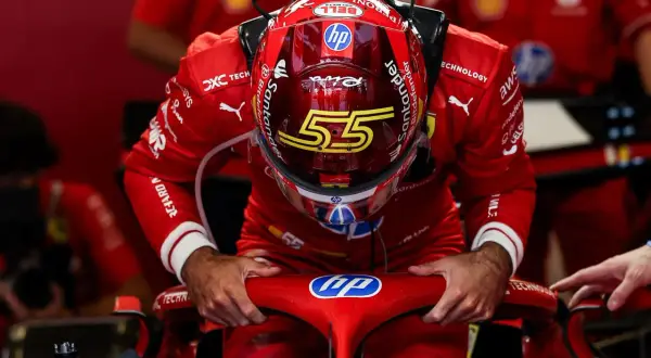 Carlos Sainz, piloto de Ferrari, se inclina sobre el volante de su monoplaza, con el casco rojo y el número 55.