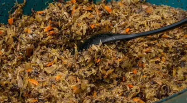 Pyszne, domowe pierogi z kapustą i grzybami, gotowe do podania. Czarna łyżka miesza aromatyczny farsz.