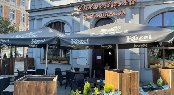 Zewnętrzny ogródek restauracji "Dolnośląska" z parasolami Kozel i stolikami.