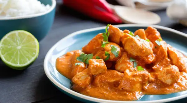 Un saporito spezzatino di pollo in salsa cremosa, guarnito con prezzemolo fresco, accompagnato da riso bianco e spicchio di lime.