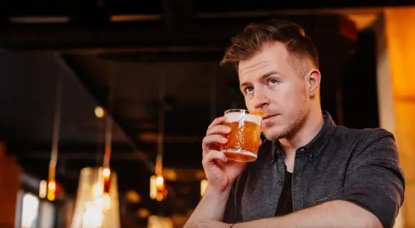Mężczyzna popija drinka, który wygląda jak klasyczny whisky sour. Idealny przepis na wieczór.