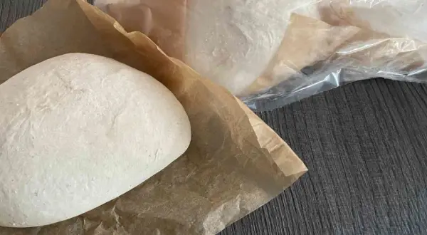 Frische Pizzaböden, bereit für das Pizzateig einfrieren. Einer liegt auf Backpapier, weitere sind in Folie verpackt.