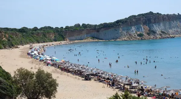 Piękna plaża na wyspie Kos, pełna ludzi kąpiących się i opalających. Uważaj na słońce i tłumy, by w pełni cieszyć się wakacjami.