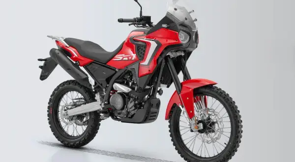 Czerwony motocykl turystyczny z czarnymi oponami terenowymi i dużą szybą.