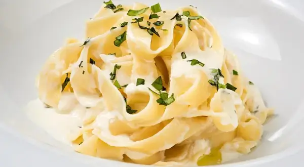 Kremowy makaron tagliatelle z sosem mascarpone i posiekaną natką pietruszki.