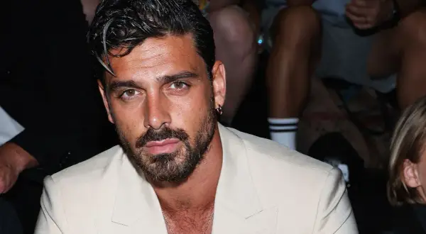 Uomo con capelli sfumati corti, barba curata e un completo chiaro.