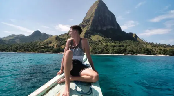 Mann auf Boot vor Bergkulisse in Indonesien. Tolle Reisetipps für dieses Inselparadies!