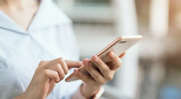 Dłoń trzyma telefon, szukając instrukcji, jak wyłączyć tryb awaryjny w telefonie.