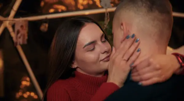 Bliska, intymna chwila pary. Ona zamyka oczy, dotykając jego policzka. Sekret jak rozkochać w sobie faceta na odległość? Bliskość, nawet w oddali.