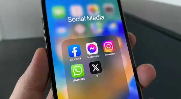 Na ekranie iPhone'a widać folder "Social Media" z ikonami Facebook, Messenger, Instagram, WhatsApp i X. Dowiedz się, jak włączyć powiadomienia Messenger.