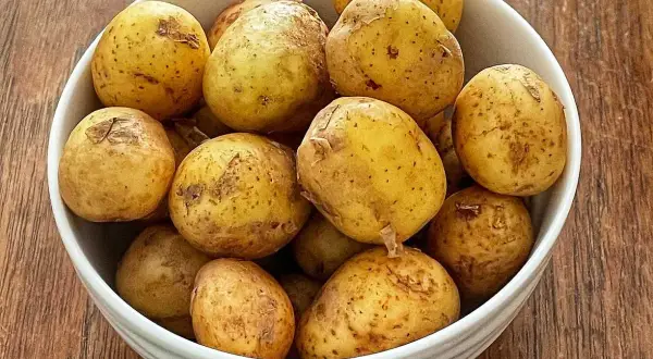 En skål med färskpotatis, redo att koka. Perfekt för en svensk sommarmåltid.