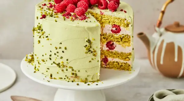 Ein köstlicher Pistazien Cheesecake mit frischen Himbeeren und gehackten Pistazien, bereit zum Servieren.