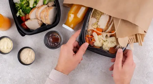 Dwa pudełka z jedzeniem na wynos: kurczak z ryżem i warzywami, sosy, sok. Idealny lunch co to?