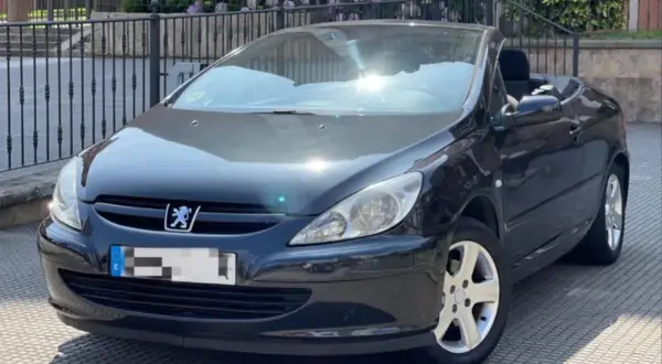 Svart Peugeot 307 CC cabriolet med taket nere. Solen reflekteras i vindrutan, kanske ett tecken på ett kommande peugeot 307 cc problem?
