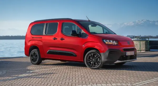 Fiat Qubo rosso fiammante parcheggiato sul lungolago, con montagne innevate sullo sfondo. Le diverse fiat qubo motorizzazioni offrono versatilità.