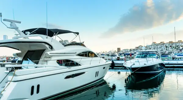 Luksusowe jachty cumują w słonecznym Puerto Banús. Błękitne niebo i spokojna woda odbijają białe kadłuby.